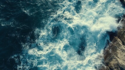 Aerial view of ocean waves crashing against rocky shore.
