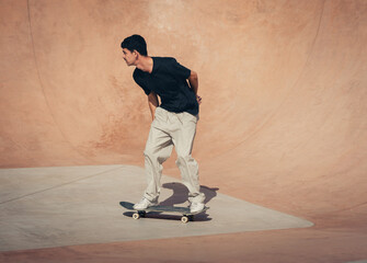 young skater wearing black tshirt skating inside a bowl in a skate park. 