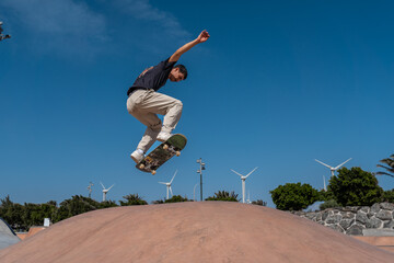 young skater wearing black tshirt jumps a ramp in a skate park.