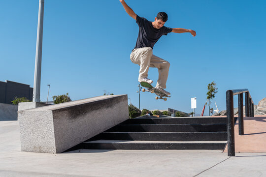 young skater wearing black tshirt jumps a staircase in a sunny day. movement 2