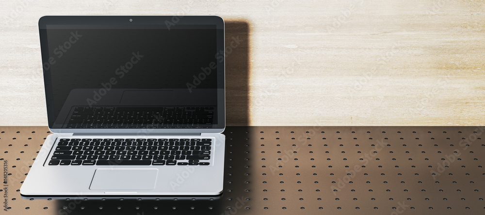 Poster open laptop with blank screen on perforated metallic surface and light wooden wall background. moder