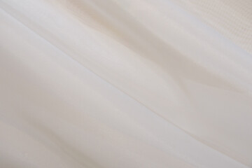 Soft beige fabric gracefully draped on a smooth surface in natural light