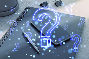 Holographic question marks over a notebook, smartphone, and pen on a desk.