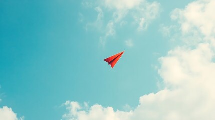 Red paper plane flies in blue sky.