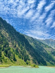 Fototapeta premium Serene Mountain Landscape with River and Blue Sky
