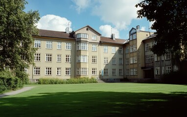 A stylish Scandinavian apartment building with light gray and dark beige elements, light olive-yellow walls, a manicured green lawn, and a bright blue sky