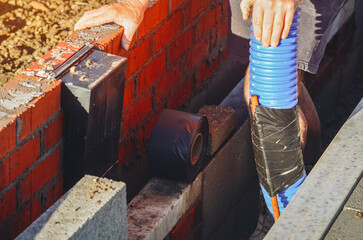 bricklayer laying bricks with blue tubing at a building site during the day