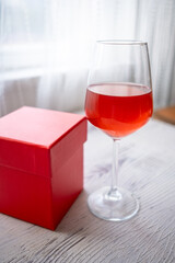 glass of wine on the table and gift red box