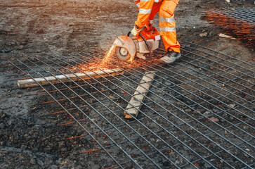 Builder cutting rebar with machine at site during daylight hours
