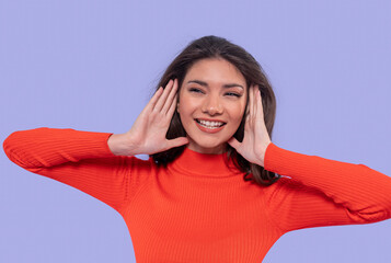 Smiling woman in bright orange sweater conveys happiness against a lilac background