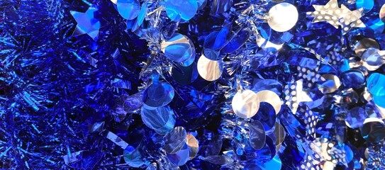 Abstract blue winter background with brigt blue sparkling tinsel close up image, decoration for Christmas tree, hapy winter mood