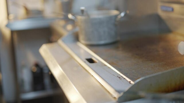 A dirty stove top with a pot on it. The stove top is covered in grime and the pot is sitting on top of it. The pot is filled with food and the stove top is in need of a good cleaning