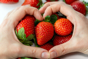 Female hands heart in front of ripe organic strawberry, harvesting