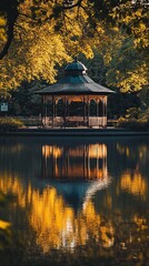 Fototapeta premium Gazebo reflected in a calm pond surrounded by golden autumn trees.