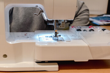 Man using a sewing machine with a garment, for repair work, customization, creation, upcycling