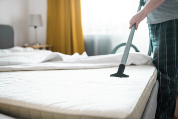 Male worker cleans a mattress with professional vacuum cleaner. Mattress chemical cleaning.