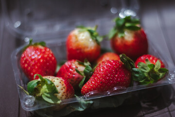 Fresh Strawberries in plastic box on wooden table. Soft focus.