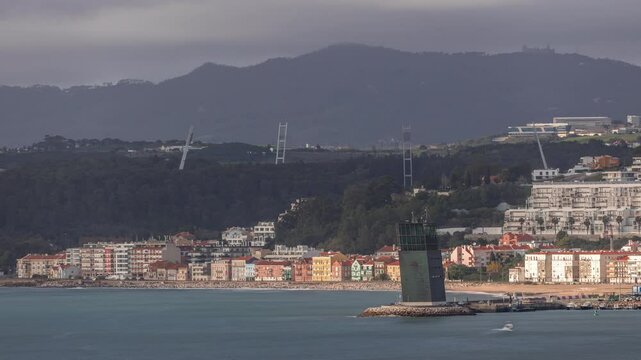 Aerial timelapse of Torre VTS de Lisboa, Lisbon's Vessel Traffic System tower for maritime coordination and safety overlooking the Tagus River. Colorful houses line the waterfront at evening. Portugal