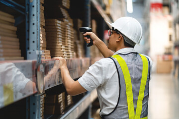 A man in a white shirt and yellow vest is scanning a barcode with a handheld device. He is wearing a hard hat and safety vest, indicating that he is working in a warehouse or industrial setting © KANGWANS