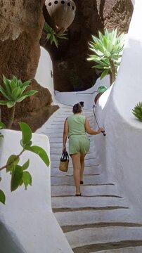 Woman walking up white staircase in lagomar lanzarote surrounded by succulent plants and rock walls