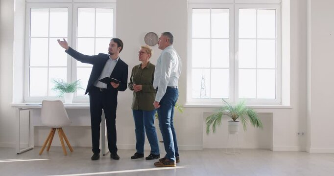 Elderly couple walks through a new home with a realtor or real estate agent. The clients carefully inspect the property, considering options for purchase in a welcoming environment.