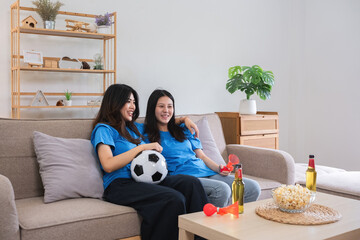 Lesbian Couple Cheering for Football Together on Cozy Sofa, Enjoying Snacks and Drinks, Celebrating Sports Enthusiasm in Modern Home Setting