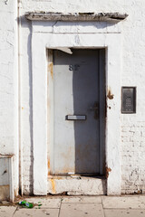 An old metal door, somewhat rusty, painted grey on a street in London