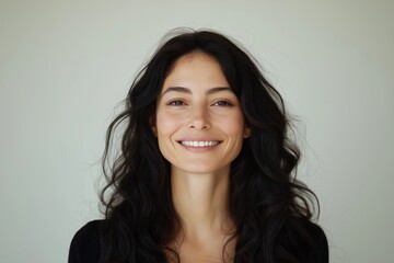 Naklejka premium Woman with long dark hair smiles at camera. Happy facial expression. Natural beauty portrait. Studio shot against neutral background. Possible uses include beauty products ads general stock photo for