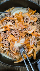 Delicious mushroom pan with noodles, mushroom dish made from fresh chanterelles with noodles in a cream sauce in the outdoor kitchen