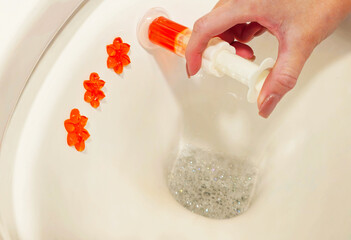 A woman's hand puts a cleaning product inside the toilet. Cleaning the toilet close-up. Women's hands