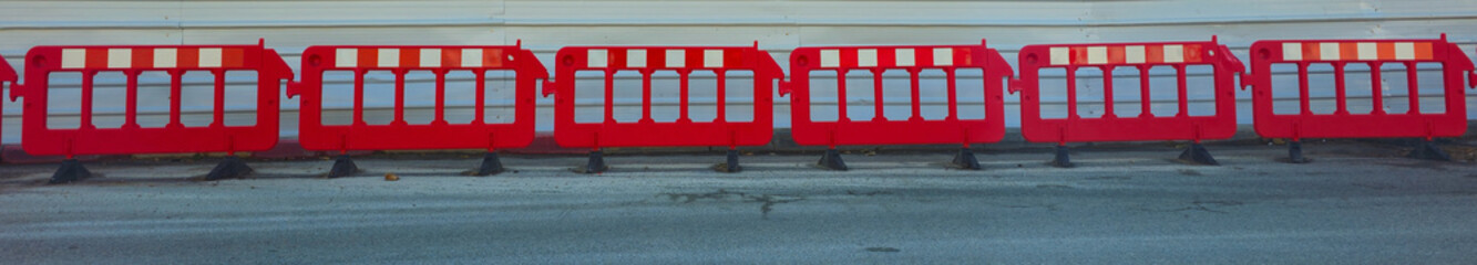 Red fence on the roadway. Barrier on the road.

