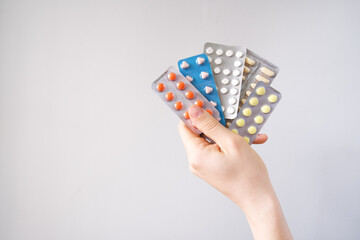 Male hand holding pills in blister packs on grey background