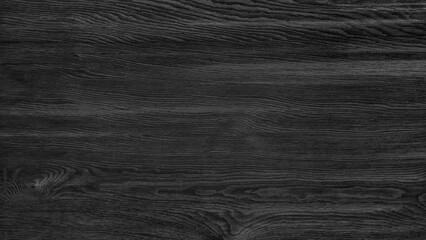 A black wooden surface with a grainy texture. The surface is dark and has a natural look