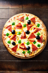 Pizza with salami and black olives. Home made food. Concept for a tasty and hearty meal. Wooden background. Top view.	