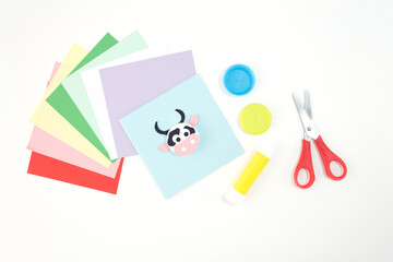 Animal crafts made from bottle caps and colored paper on a white background. Flat lay composition with scissors, glue stick, and craft materials. DIY children activity and recycling concept