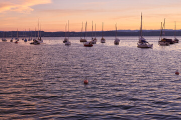 Sunset over Lake with Pier and Sailboats, Serene Waterfront Scene, Orange and Pink Sky, Calm Water, Silhouettes of Boats, Tranquil Evening, Reflections on Water, Peaceful Marina, Dusk Landscape