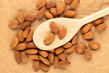 Fragrant roasted almonds with kitchen utensils on kraft paper, close-up, top view.