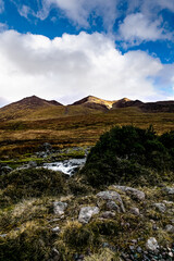 Majestic mountain landscape under a bright blue sky with wispy clouds in a serene natural setting.