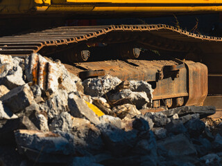 Excavator at the construction site with illustration of the rocks. Rusty excavator tracks.