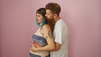 Pregnant woman with blue hair and man with beard embracing over pink background showcasing love and togetherness