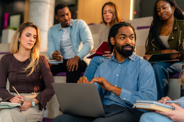 University students using laptop and taking notes during lesson