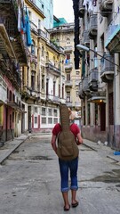 A boy with a guitar on his back walks the streets of Havana 