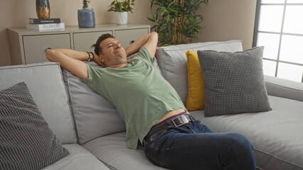 Hispanic man relaxing on a comfortable couch in a cozy living room with decorative pillows and indoor plants