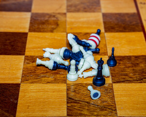 Tumbling chess pieces scattered on a wooden chessboard during a game