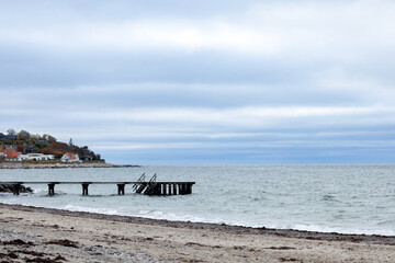 Pier with a ramp for boats and boats at the cape with a village on the North Sea coast