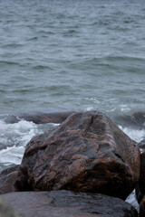 Rolled boulder of brown gneiss in the surf strip of the sea