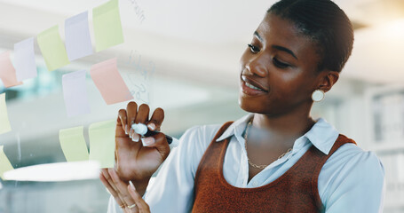 Woman, writing and notes on glass wall in office with smile for planning, review and progress at...