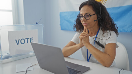 Woman voting in an argentinian electoral room with a laptop, a headset, and a ballot box,...