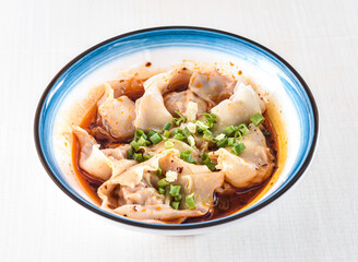 Spicy Wonton Soup in red oil with scallions served in bowl isolated on white background side view...