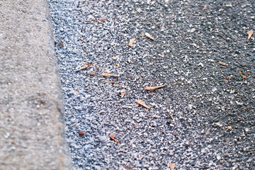 Salt crystals on an asphalt road during winter, ensuring vehicle safety and ice prevention in harsh roadside conditions. Roadside safety measures and deicing treatments for vehicles.